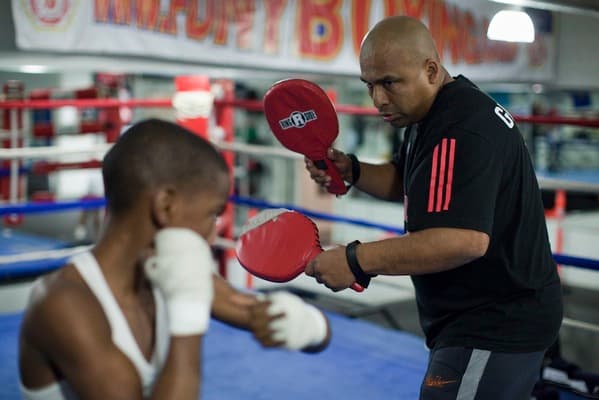 Volunteer coach training a young person at a free boxing class